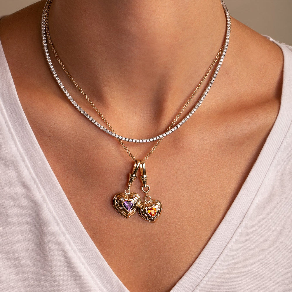 Model layering two statement heart charms in gold from the Thomas Laine True Heart collection
