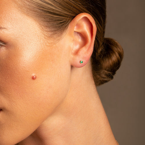 14k Yellow Gold Micro Round Domed Bezel-Set Emerald Stud Earrings on Model