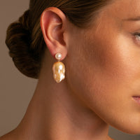 These earrings are adorned with lustrous 8-8.5 mm white freshwater pearls and crowned with golden-hued natural baroque pearl on model