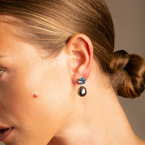 Striking Cushion Cut London Blue Topaz with contrasts with the luminous natural peacock green baroque pearl drop earring on model - Thomas Laine Jewellery