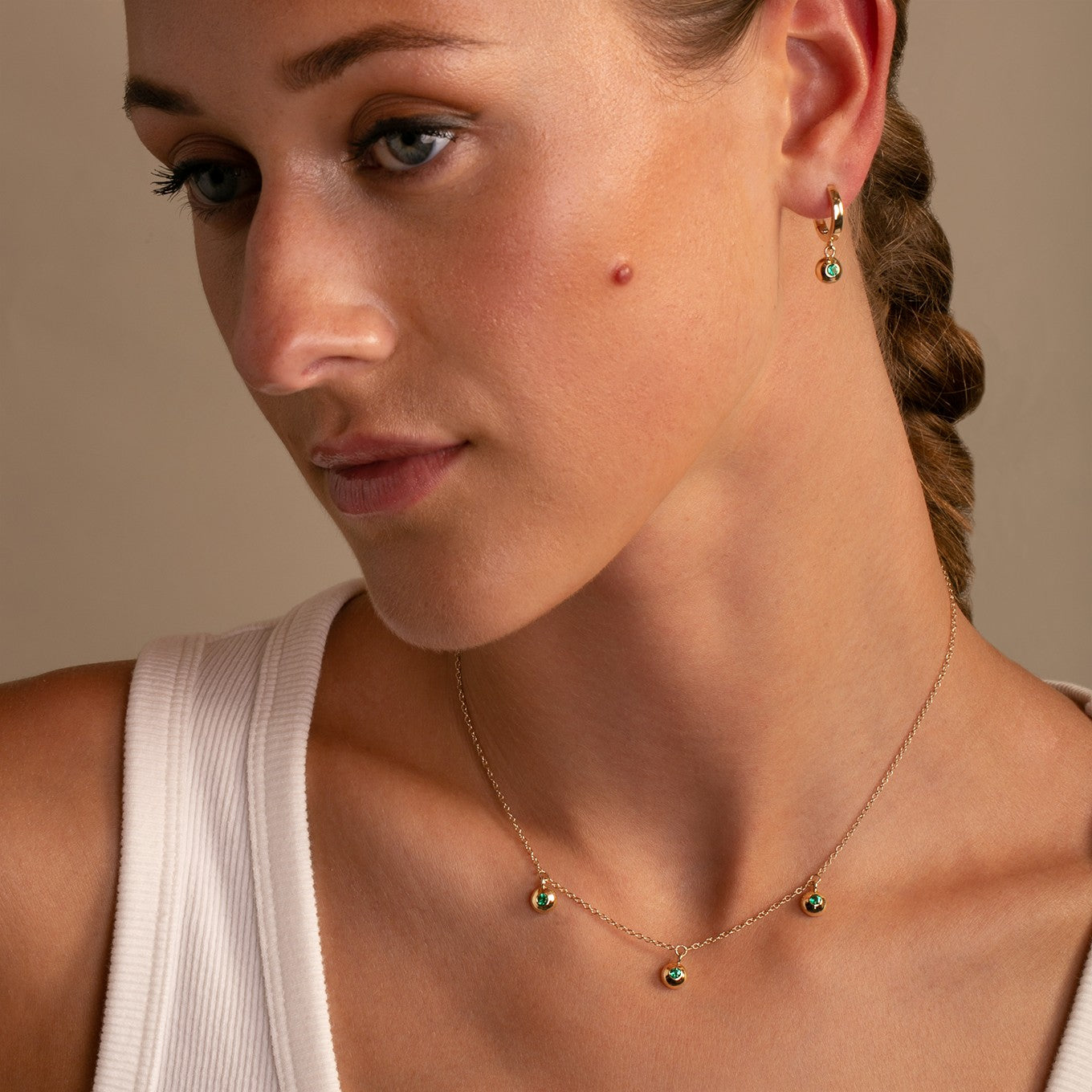 14K Yellow Gold Bezel Set Emerald Drop Hoops styled with 14K Yellow Gold Dome Bezel Set Emerald Trio Necklace on model- Thomas Laine Jewelry