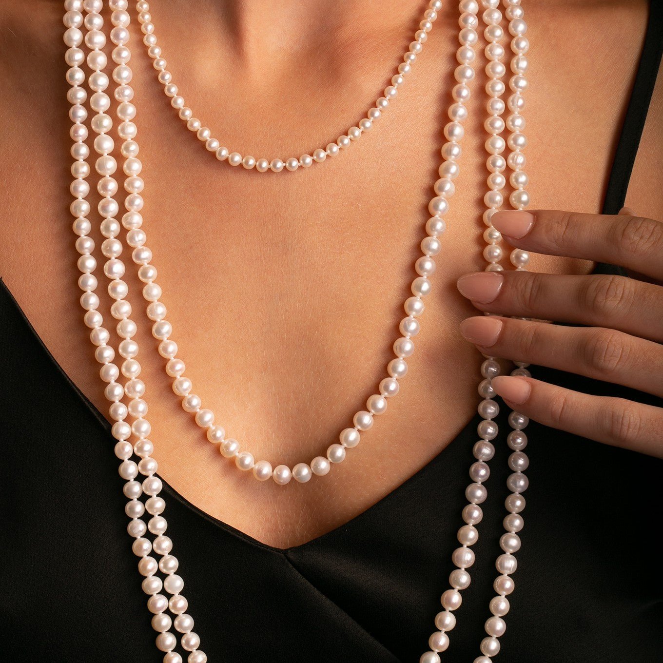 Close-up of 6–7 mm white freshwater pearls, 100 cm necklace, on model. Styled with a layered 18inch pearl strand
