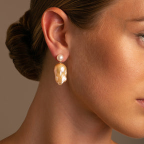  These earrings are adorned with lustrous 8-8.5 mm white freshwater pearls and crowned with golden-hued natural baroque pearl on model 