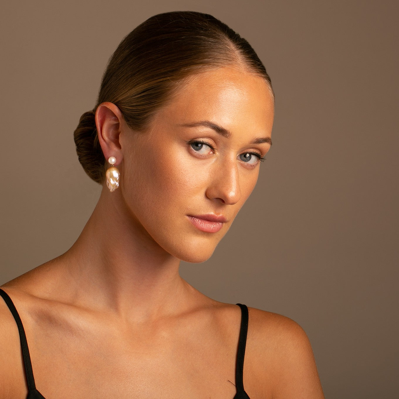 Double Bubble earrings pair a classic 8-8.5 mm white freshwater pearl with a distinctive golden baroque pearl on a 14k yellow gold post. These earrings make a sophisticated statement with their natural, lustrous dangle. Shown here on model