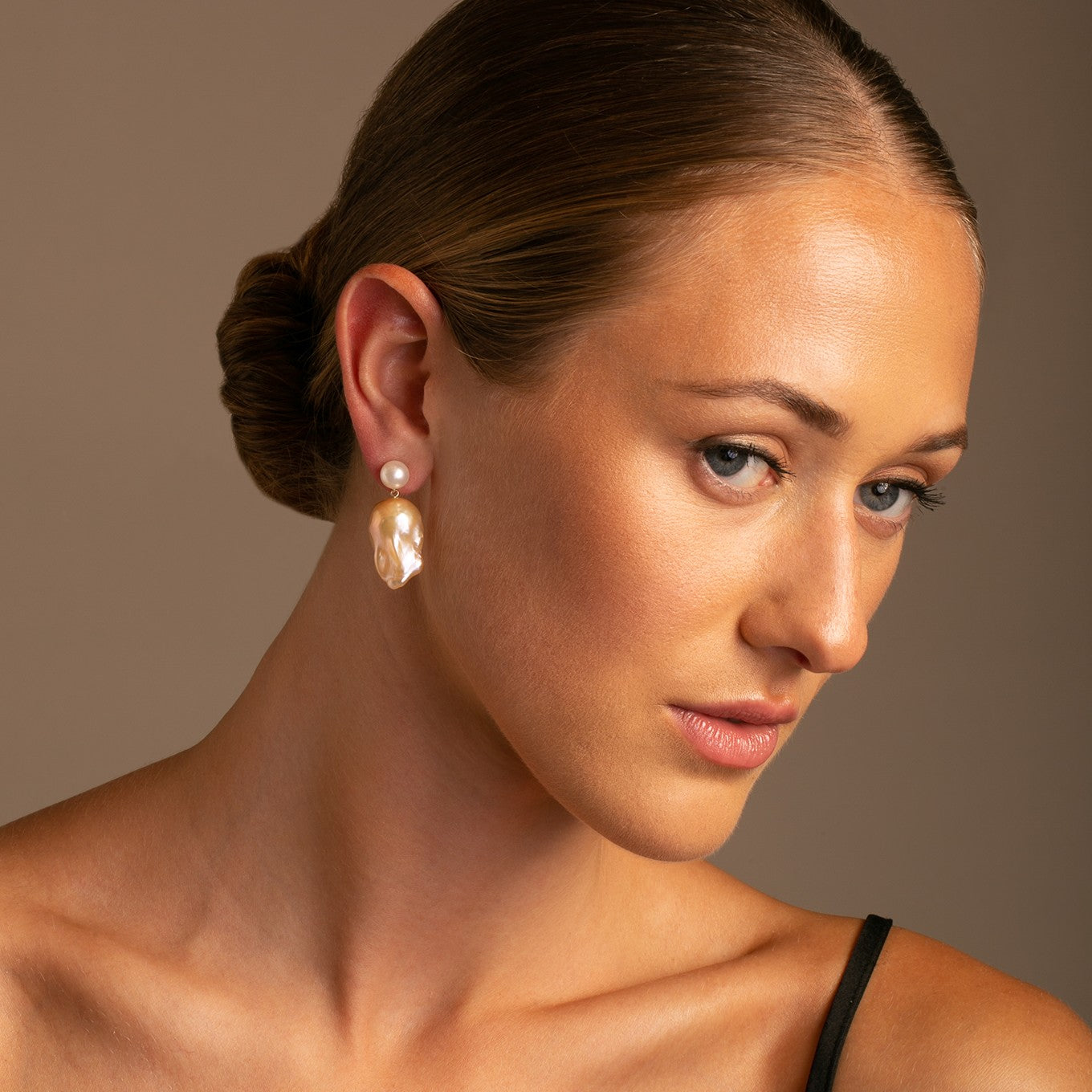 The Double Bubble earrings pair a classic 8-8.5 mm white freshwater pearl with a distinctive golden baroque pearl on a 14k yellow gold post on model