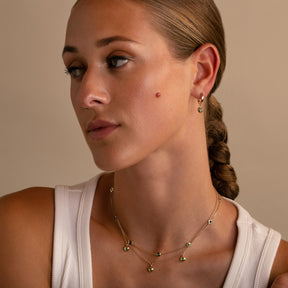 Layered 14K Yellow Gold Ten Stone Bezel Set Emerald Necklace with 14K Yellow Bezel Set Emerald Drop Hoops on model-Thomas Laine Jewelry