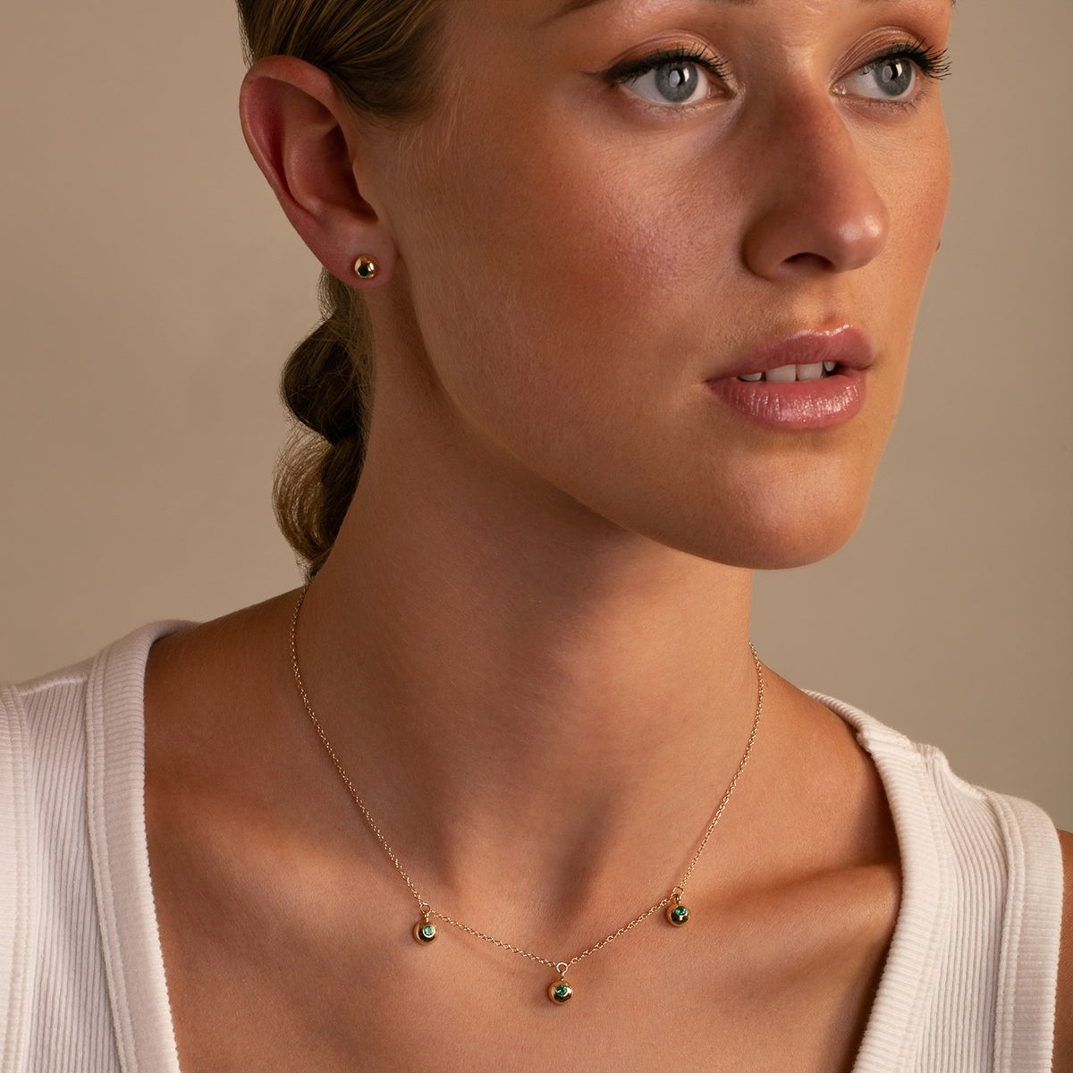 14K Yellow Gold Bezel Set Emerald Drop Neckace  with bezel set stud earrings on model- Thomas Laine Jewelry