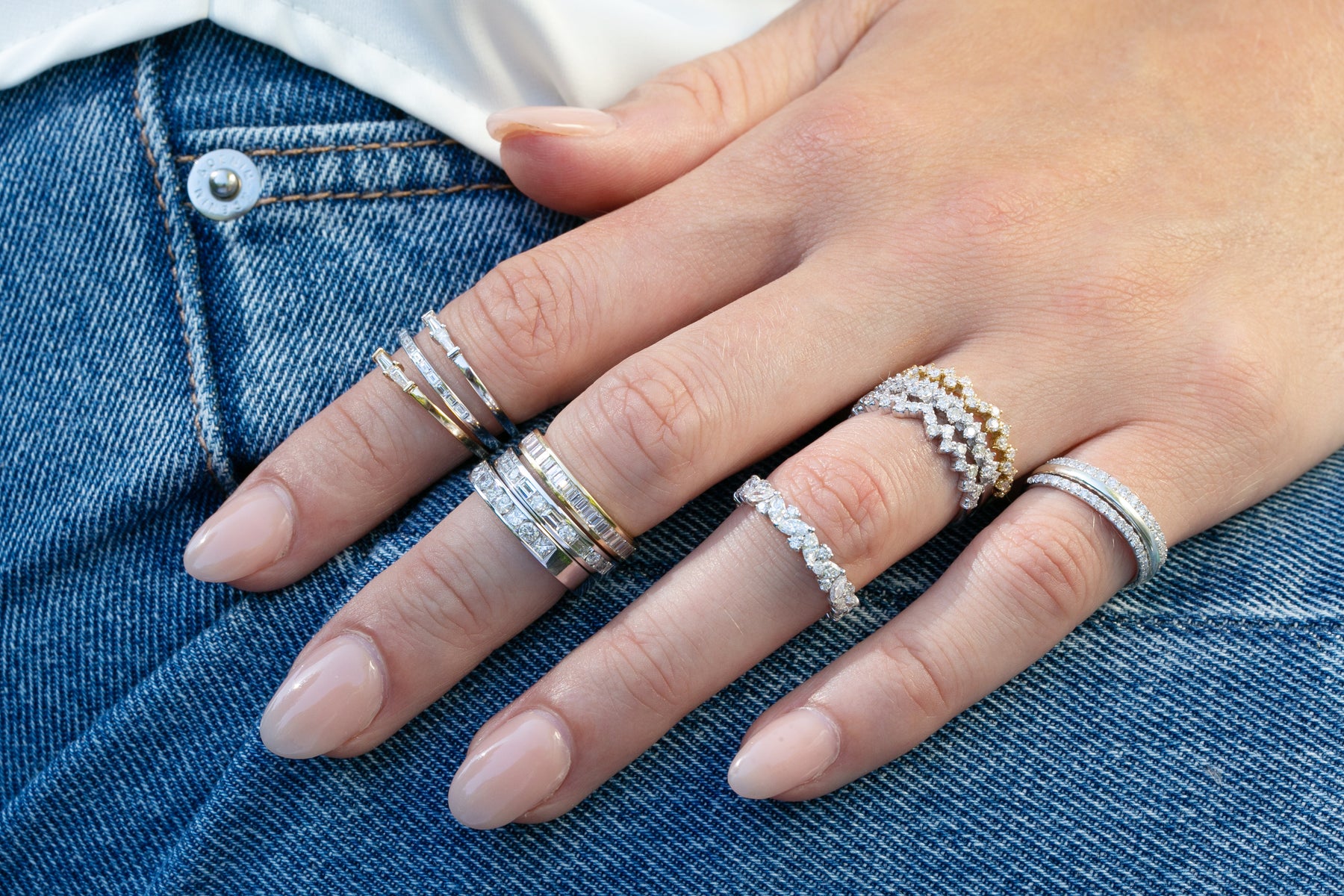 18K Gold Petite Double Baguette Diamond Stacking Band styled in a casual style with multiple other diamond bands layered on model wearing denim jeans. Thomas Laine Jewelry